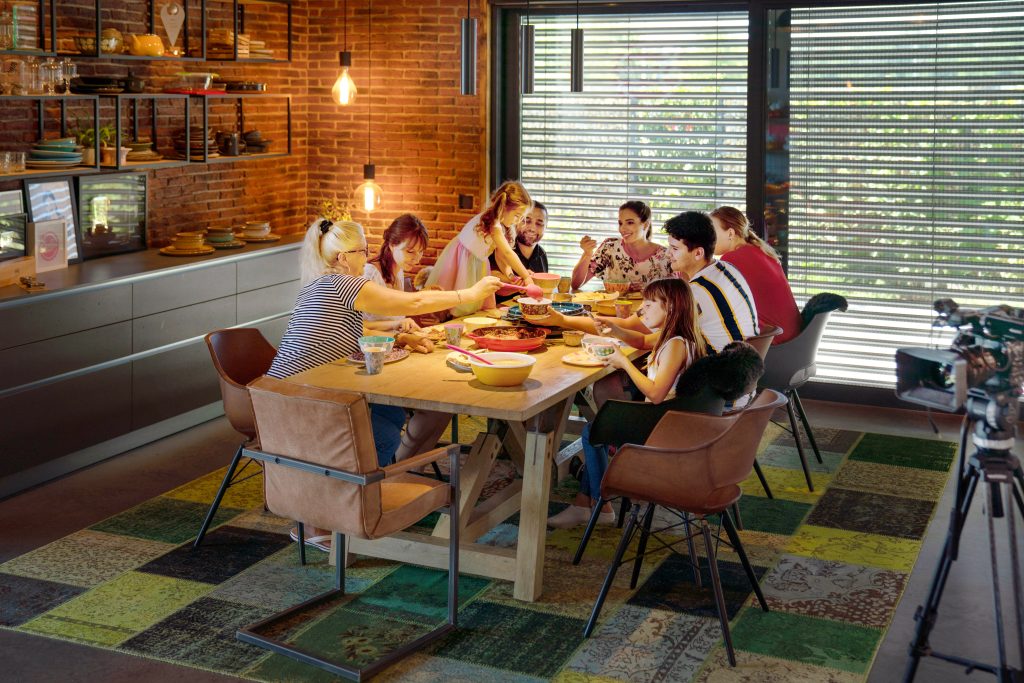 a well lit family dining table with people einjoying dinner